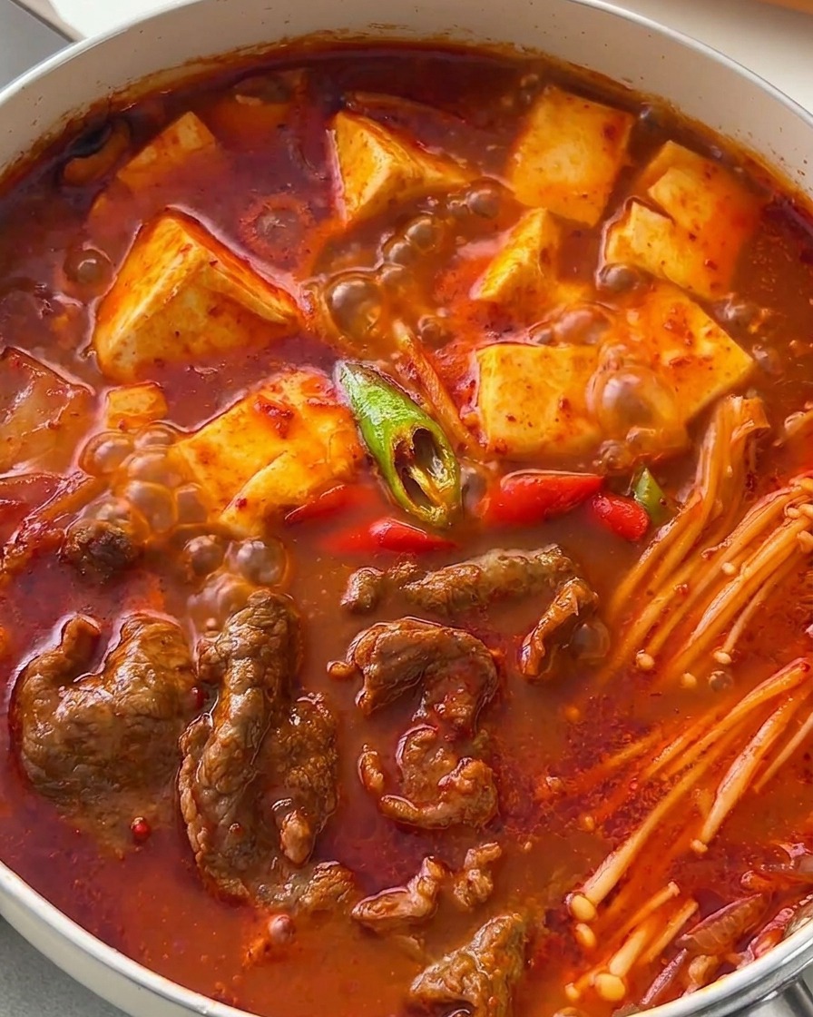 완성된 소고기 순두부찌개 위에 어긋썰기한 청양고추와 홍고추를 뿌린 모습.