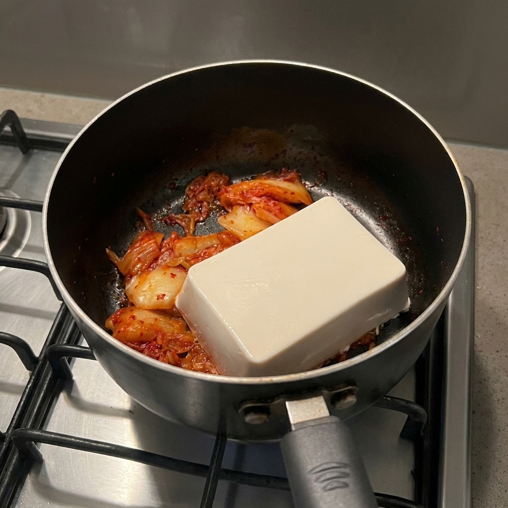 냄비에 볶아둔 김치 위에 큼지막하게 얹은 하얀 순두부 블록