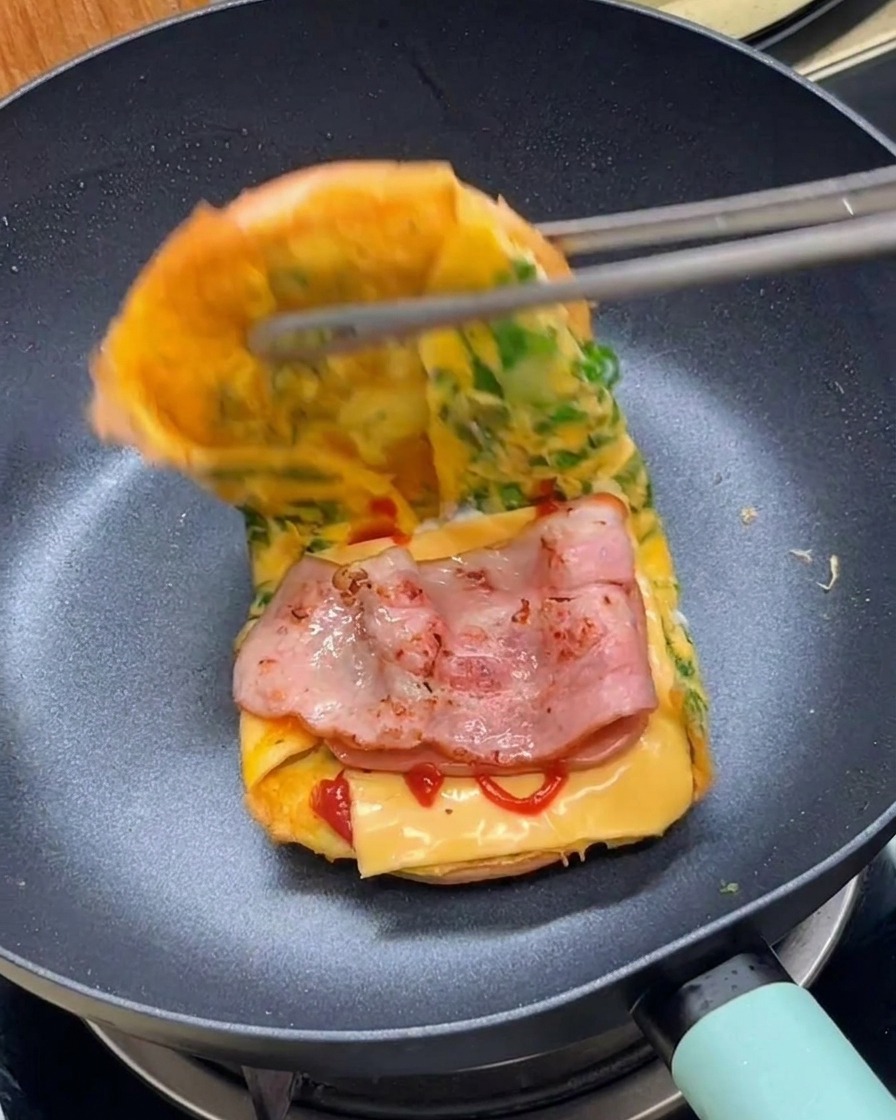 집게를 이용해 조식 버거를 반으로 접어 완성하는 모습.
