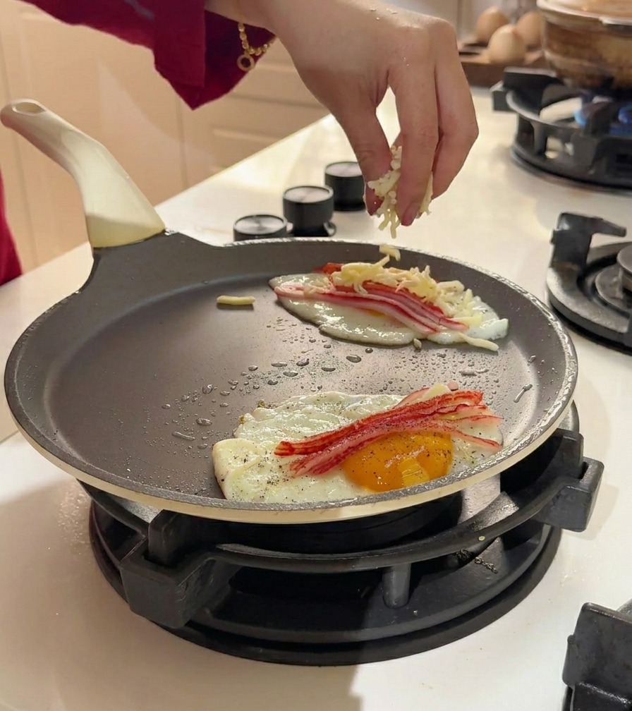 팬 안의 계란과 게맛살 위에 모짜렐라 치즈 가루를 듬뿍 뿌리는 모습