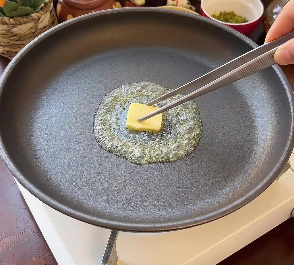 녹은 버터가 깔린 프라이팬 위에 단면이 아래로 가도록 놓인 두 개의 둥근 버거 번.