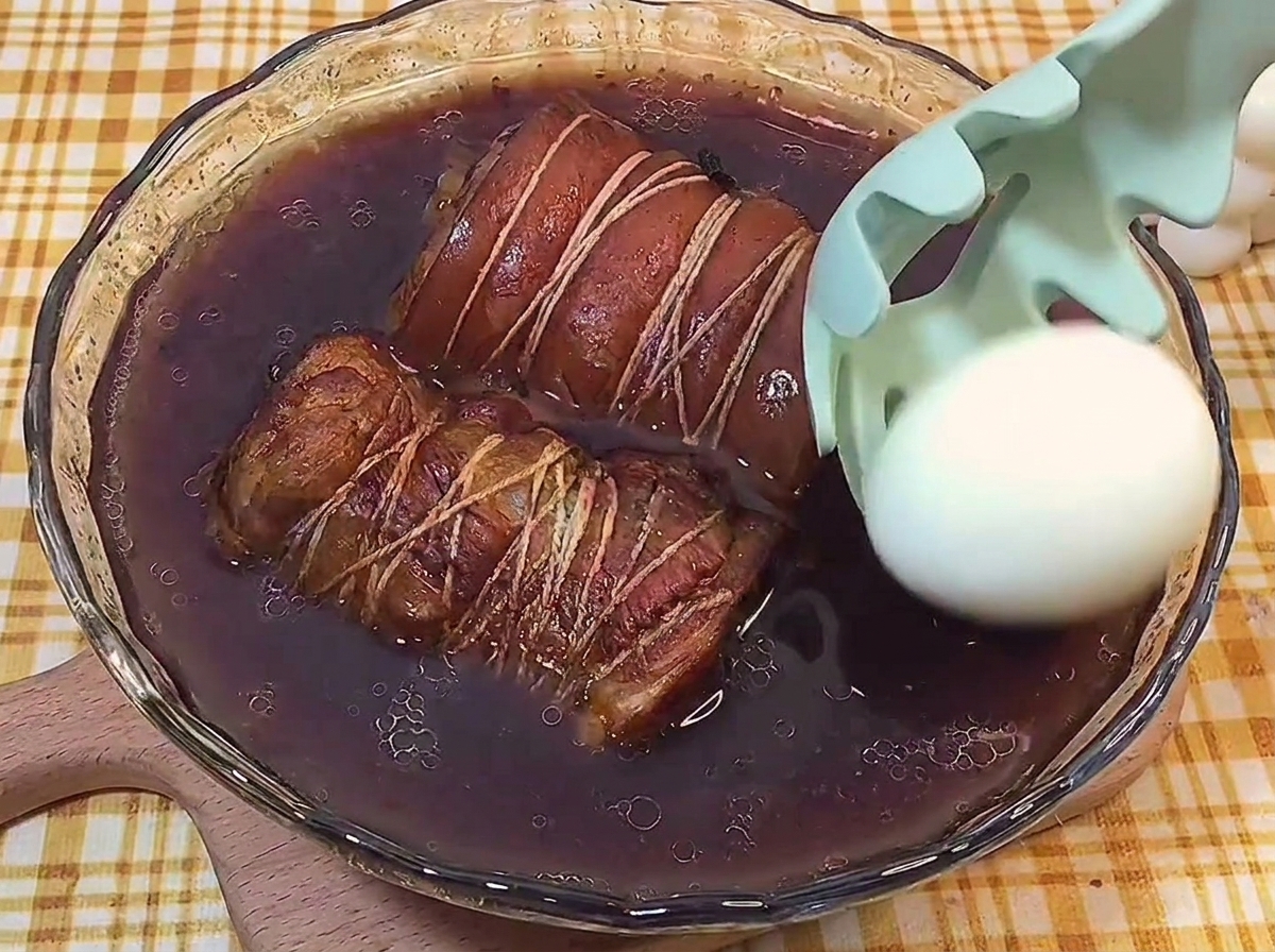 껍질을 깐 삶은 달걀을 고기가 담긴 조림장에 함께 넣는 모습.