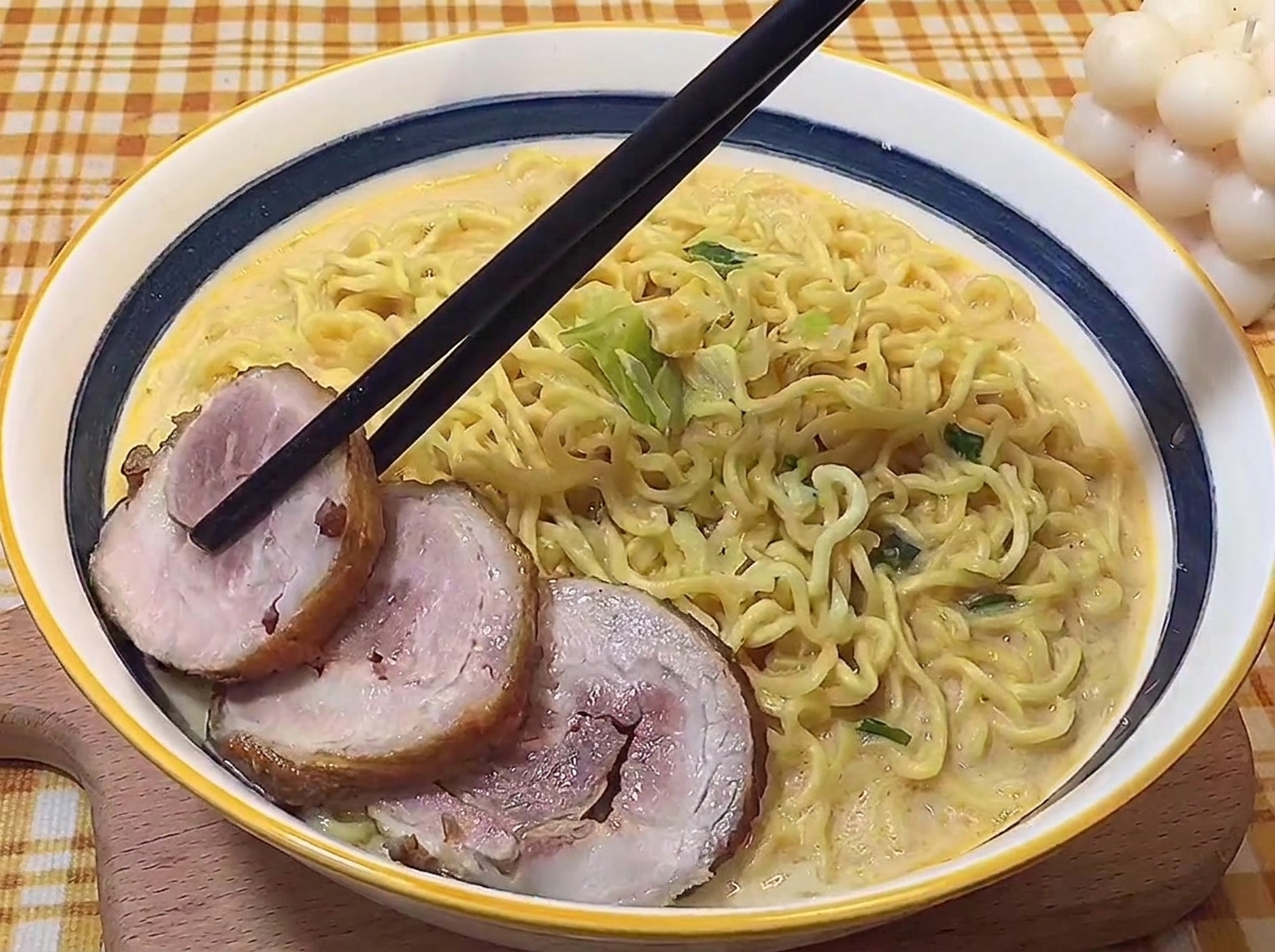 완성된 라멘 위에 젓가락으로 차슈를 정갈하게 올리는 모습.