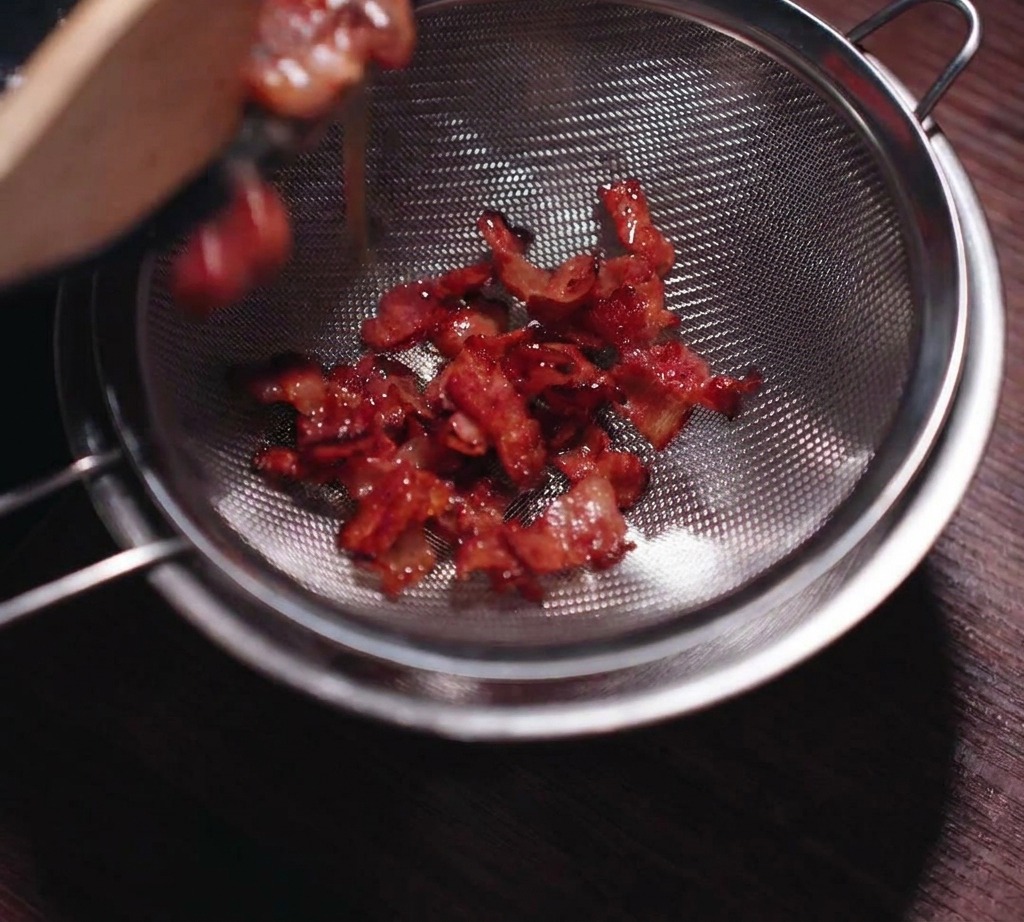체에 걸러 베이컨 조각과 기름을 분리하는 과정