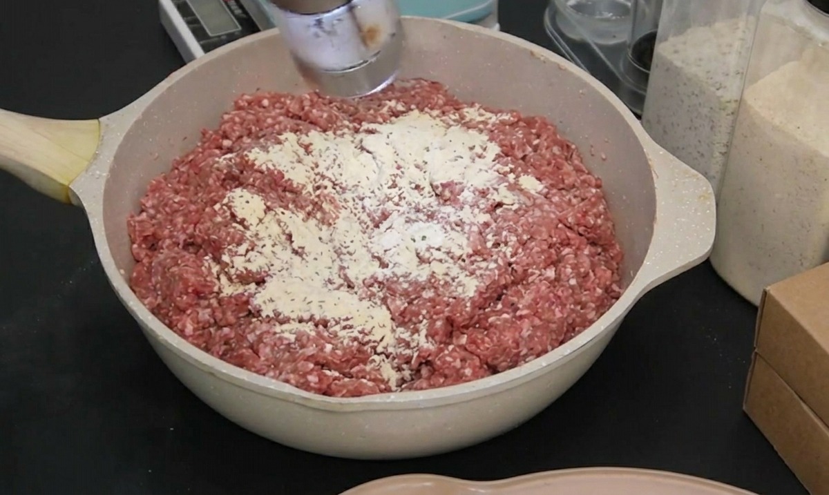 검은색 장갑을 낀 손으로 고기 위에 천일염을 갈아 넣는 모습