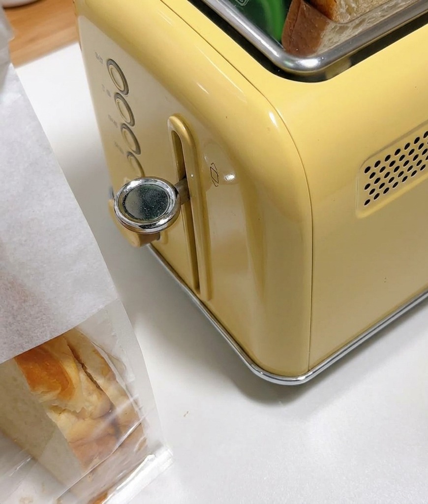 노란색 빈티지 토스터기 투입구에 담긴 두꺼운 식빵.