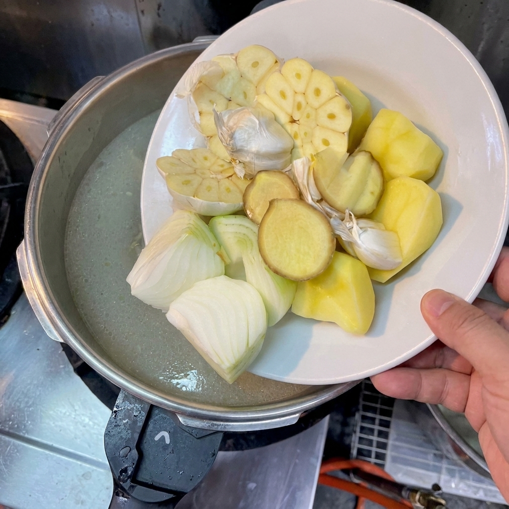 감자, 양파, 생강, 마늘을 육수에 넣는 모습