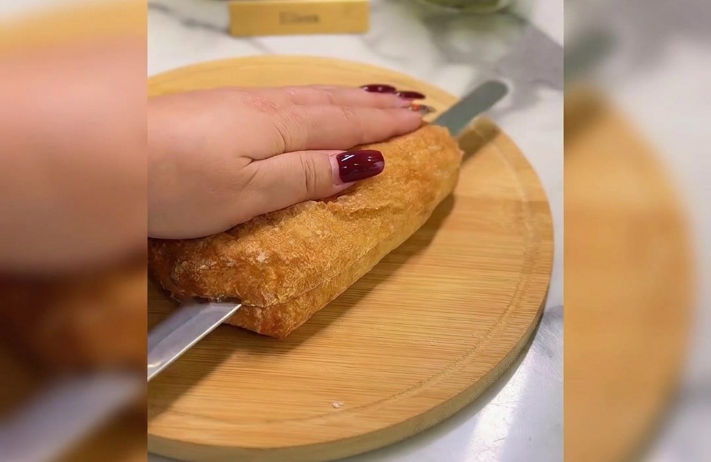 도마 위에서 빵칼을 이용해 치아바타 빵을 가로로 이등분하여 자르는 모습.