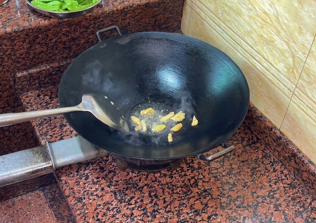 뜨겁게 달군 마른 웍에서 오리 껍질을 볶아 기름을 내는 모습.
