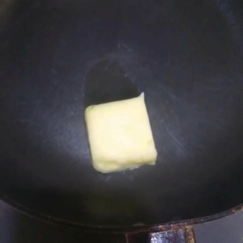 뜨거운 프라이팬 위에서 노란 버터가 지글거리며 녹는 모습.