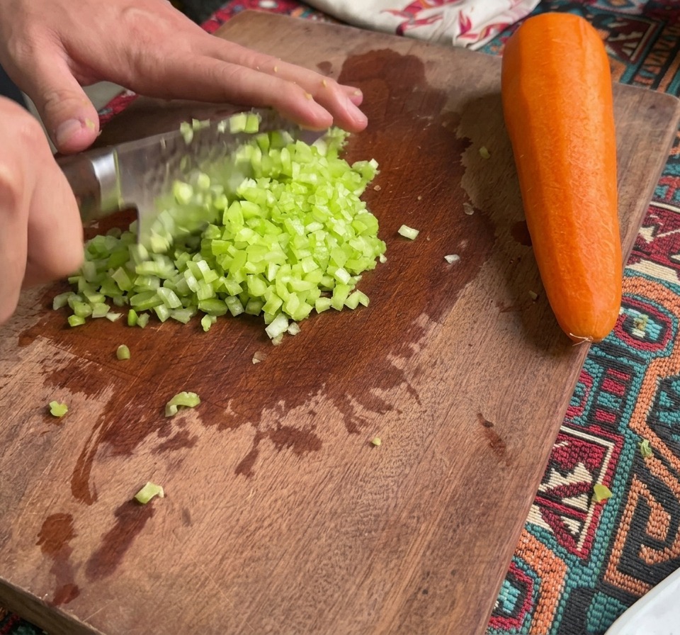 도마 위에 놓인 잘게 다진 셀러리와 당근, 그리고 온전한 당근 한 뿌리.