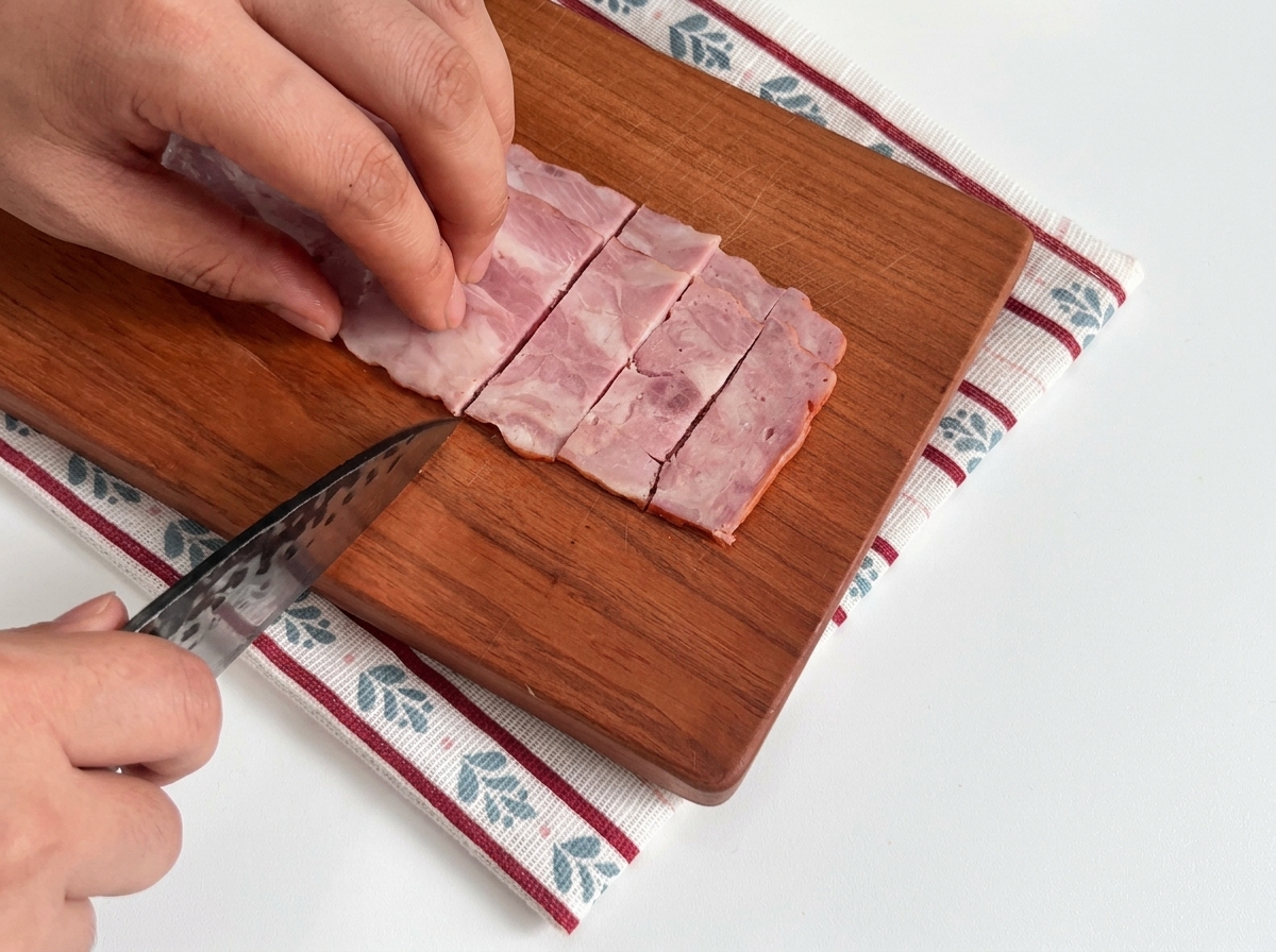 도마 위에 놓인 생 베이컨을 적당한 크기로 자르는 모습.