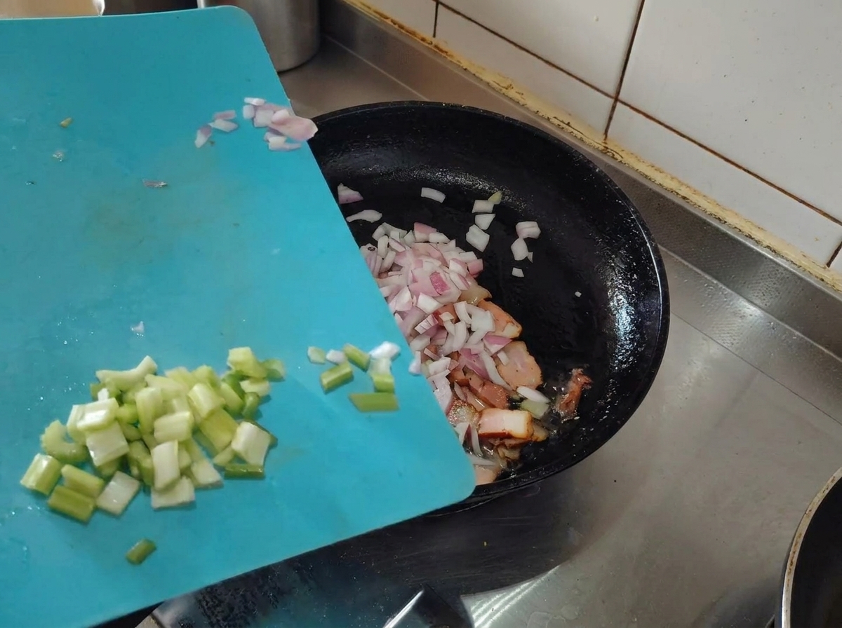 노릇하게 익은 베이컨에 다진 샬롯과 셀러리를 추가하는 모습.