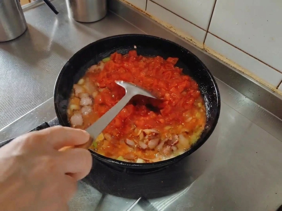 주걱으로 토마토를 으깨며 졸이는 모습.