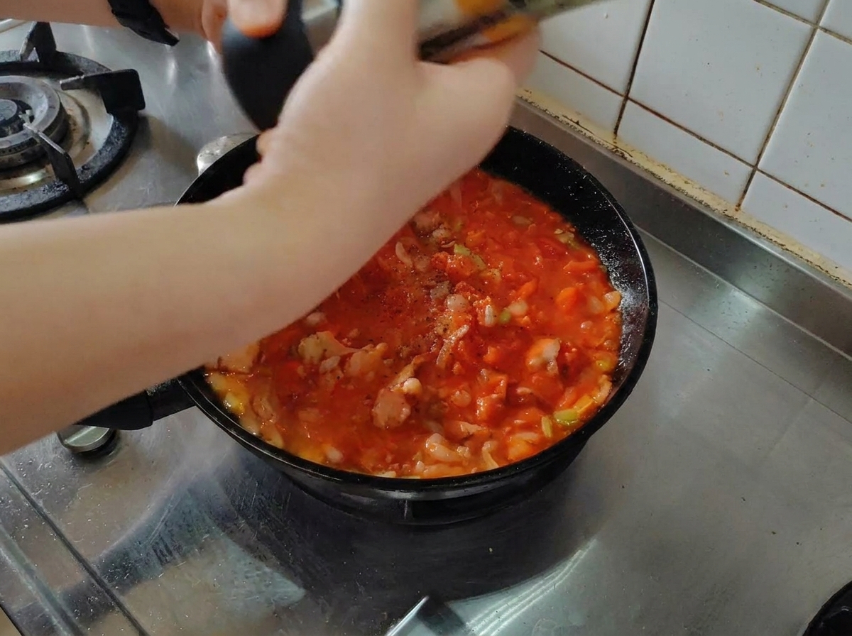 토마토 소스 위에 후추를 뿌리는 모습.