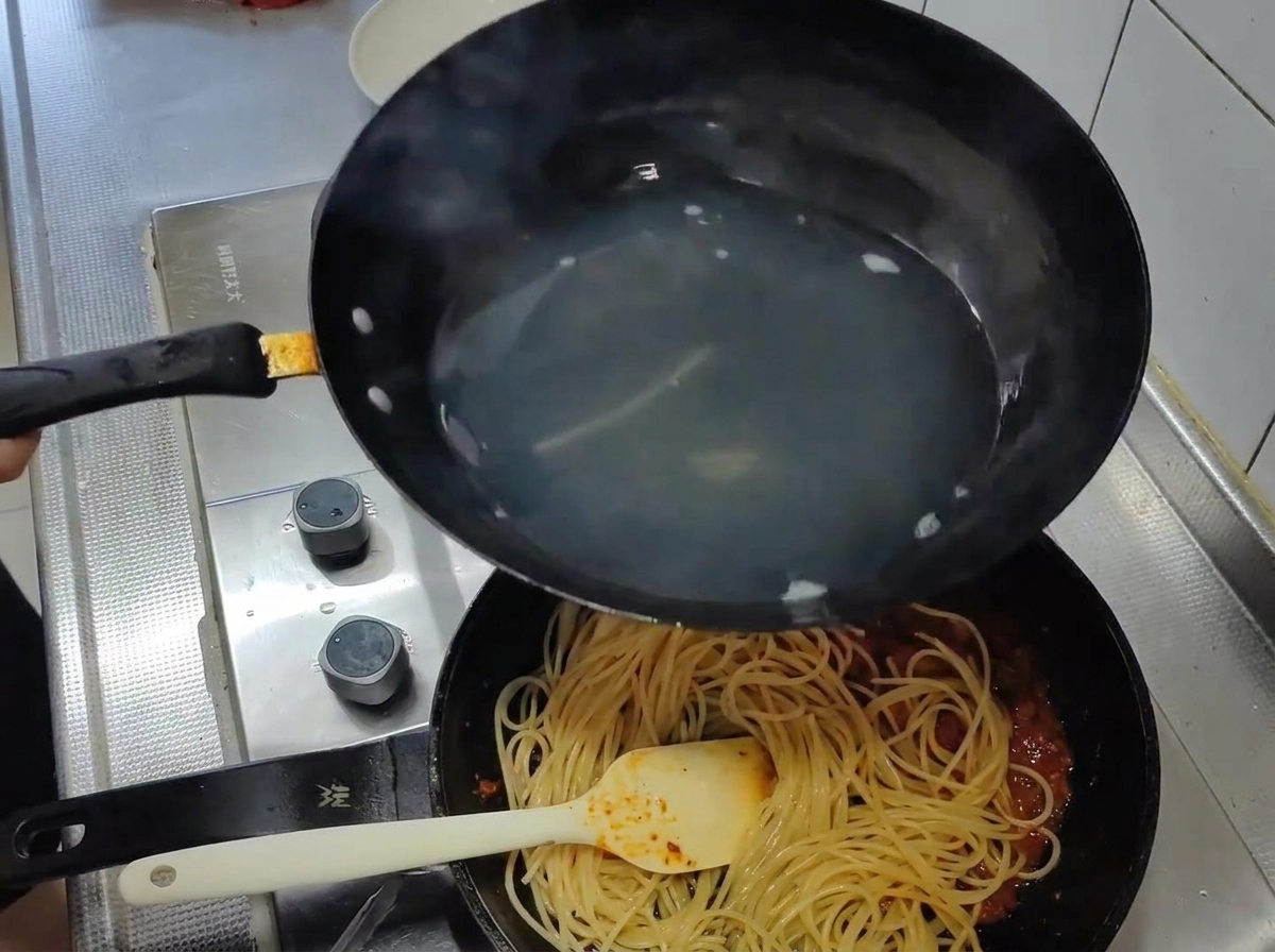 삶은 면을 토마토 소스 팬으로 옮기는 모습.