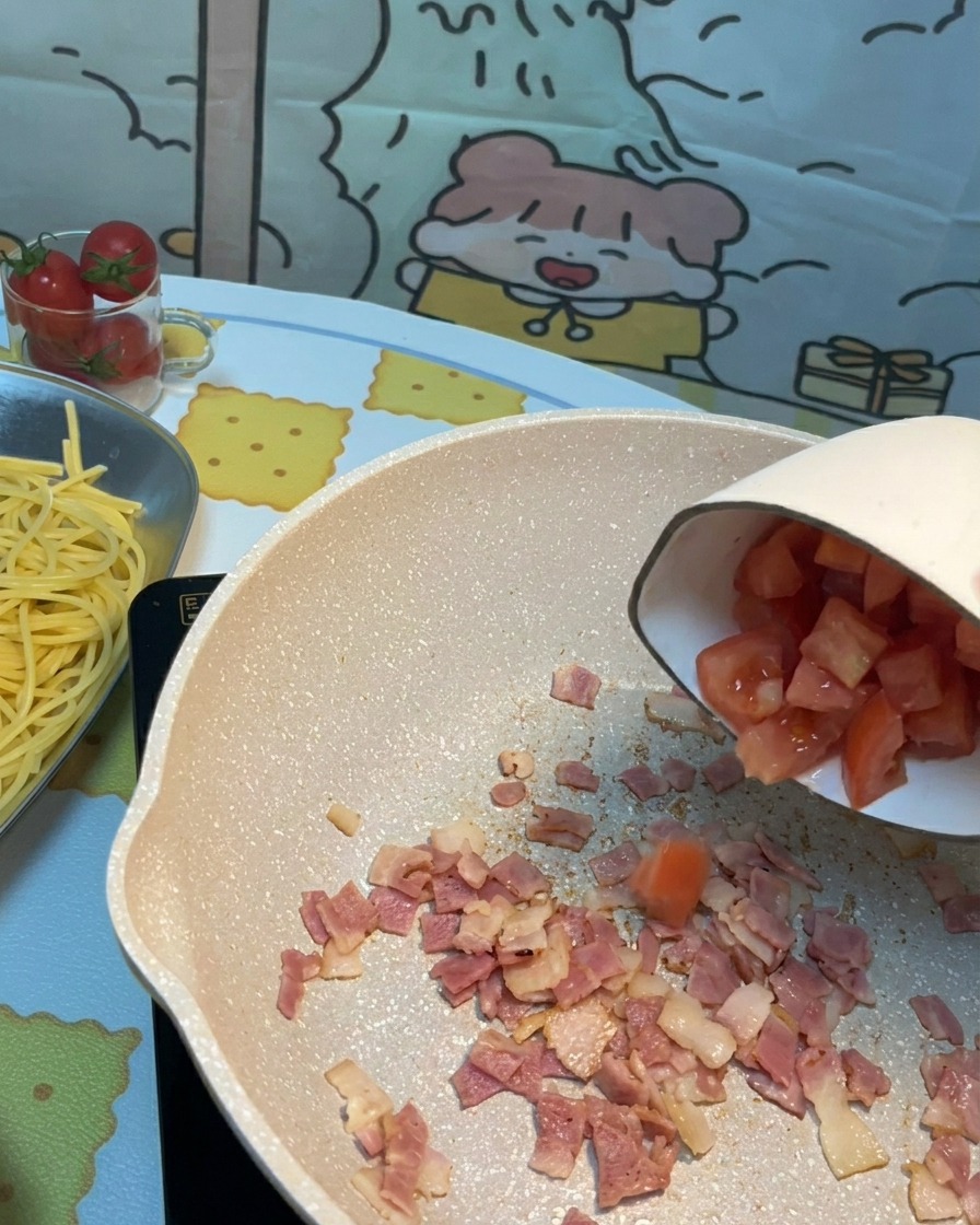 베이컨이 있는 팬에 썬 토마토를 넣는 모습.