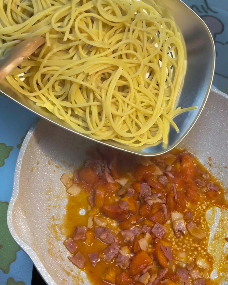 삶은 면을 토마토 베이컨 소스 팬에 옮겨 담는 모습.