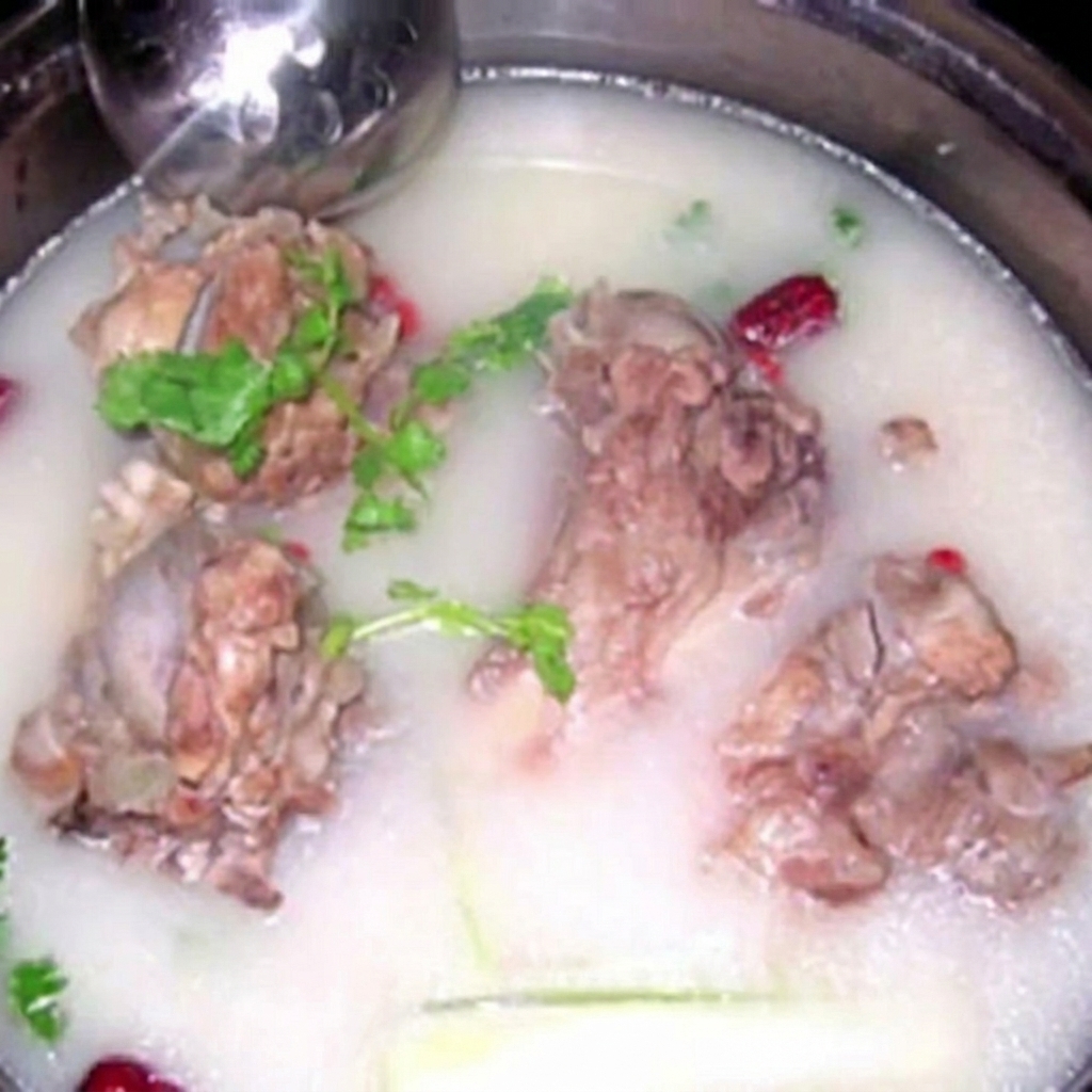 우윳빛으로 변한 진한 육수에 커다란 돼지뼈가 잠겨 있고 신선한 허브가 곁들여진 모습.