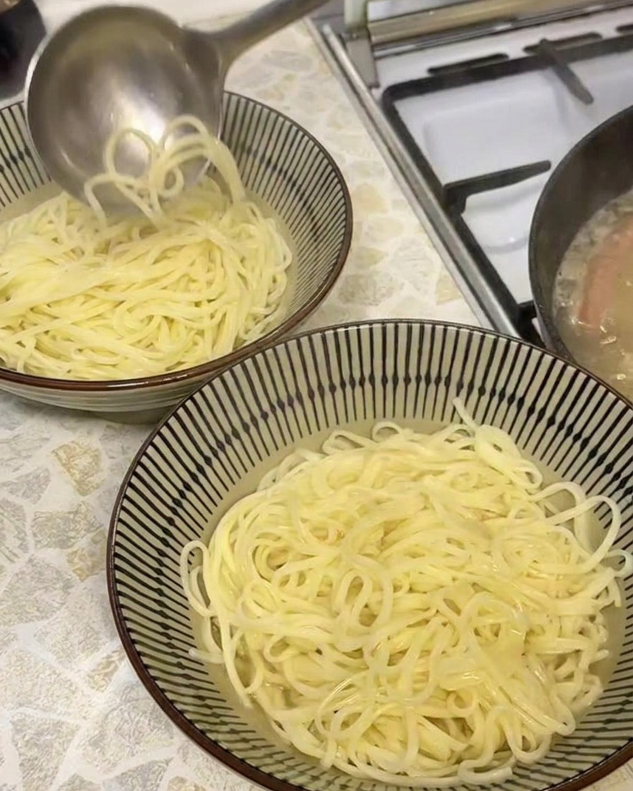 조리된 면이 담긴 그릇에 뽀얀 육수를 붓는 모습.