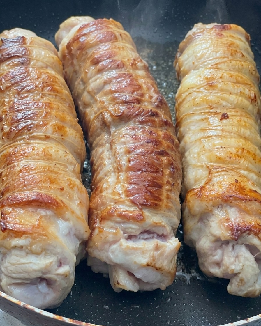 달궈진 팬에서 황금빛으로 구워지는 돌돌 말린 삼겹살의 모습.