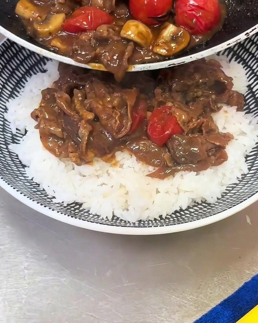 준비된 밥 위에 볶아둔 소고기와 버섯, 토마토를 얹는 모습.