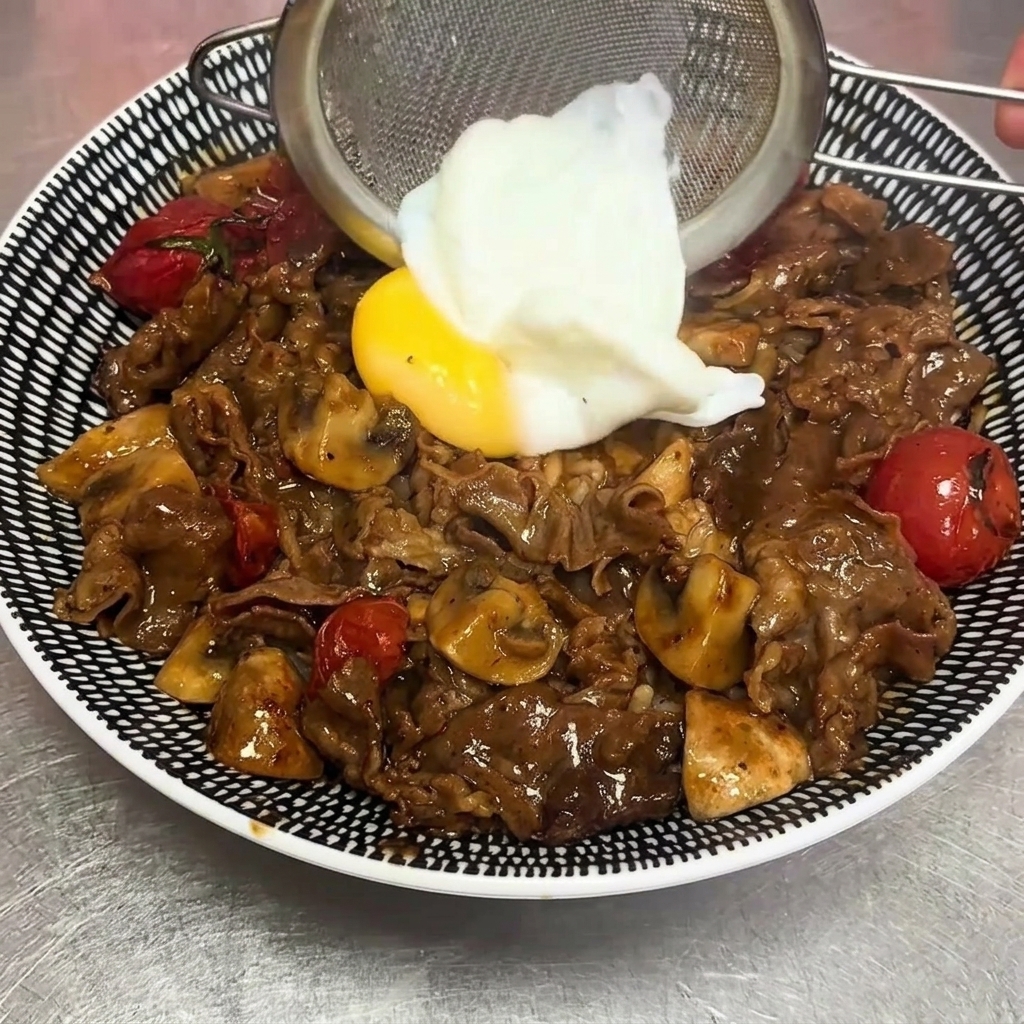 체에 밭쳐 물기를 뺀 온천 달걀을 덮밥 중앙에 조심스럽게 올리는 모습.