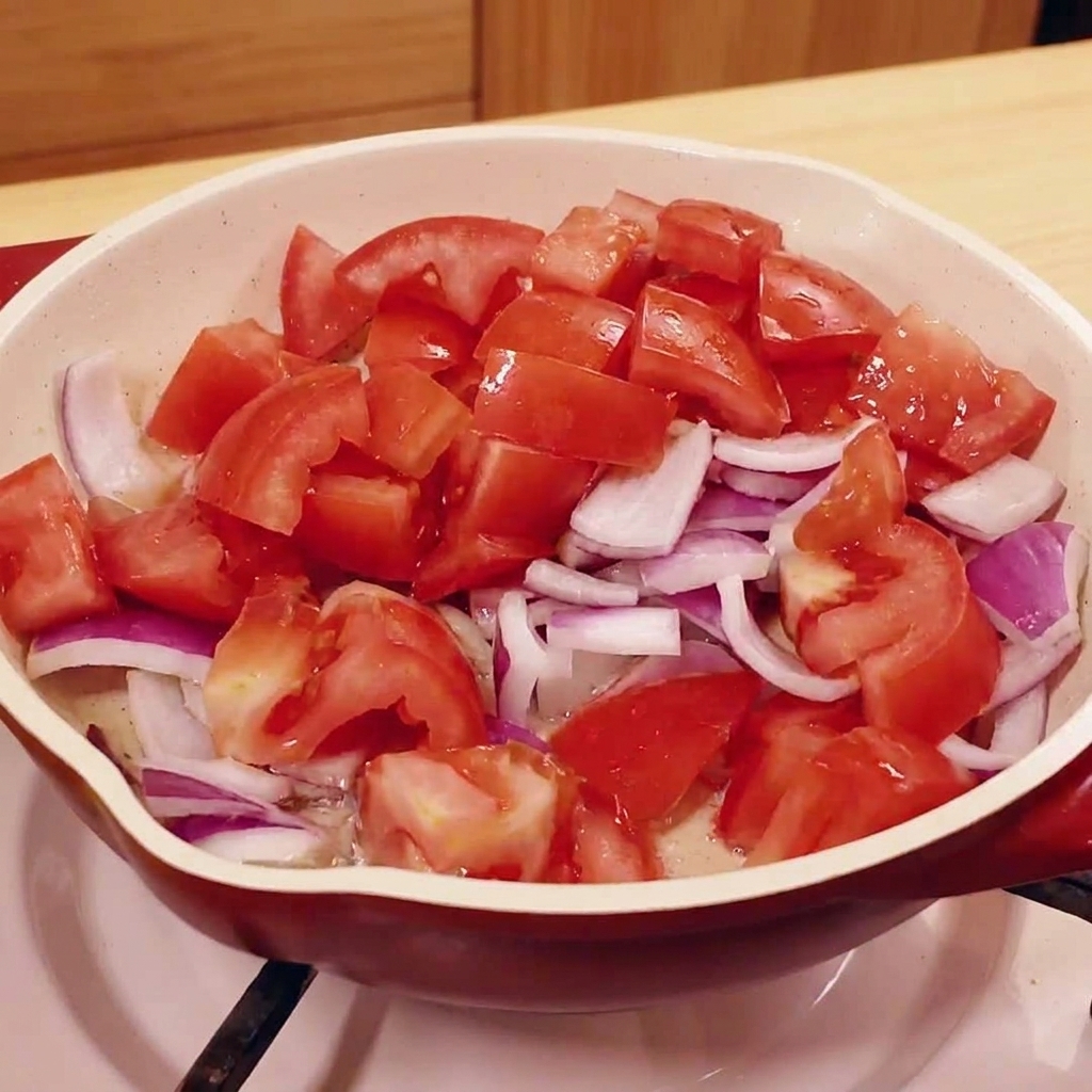 팬에서 다진 양파와 토마토를 볶는 모습