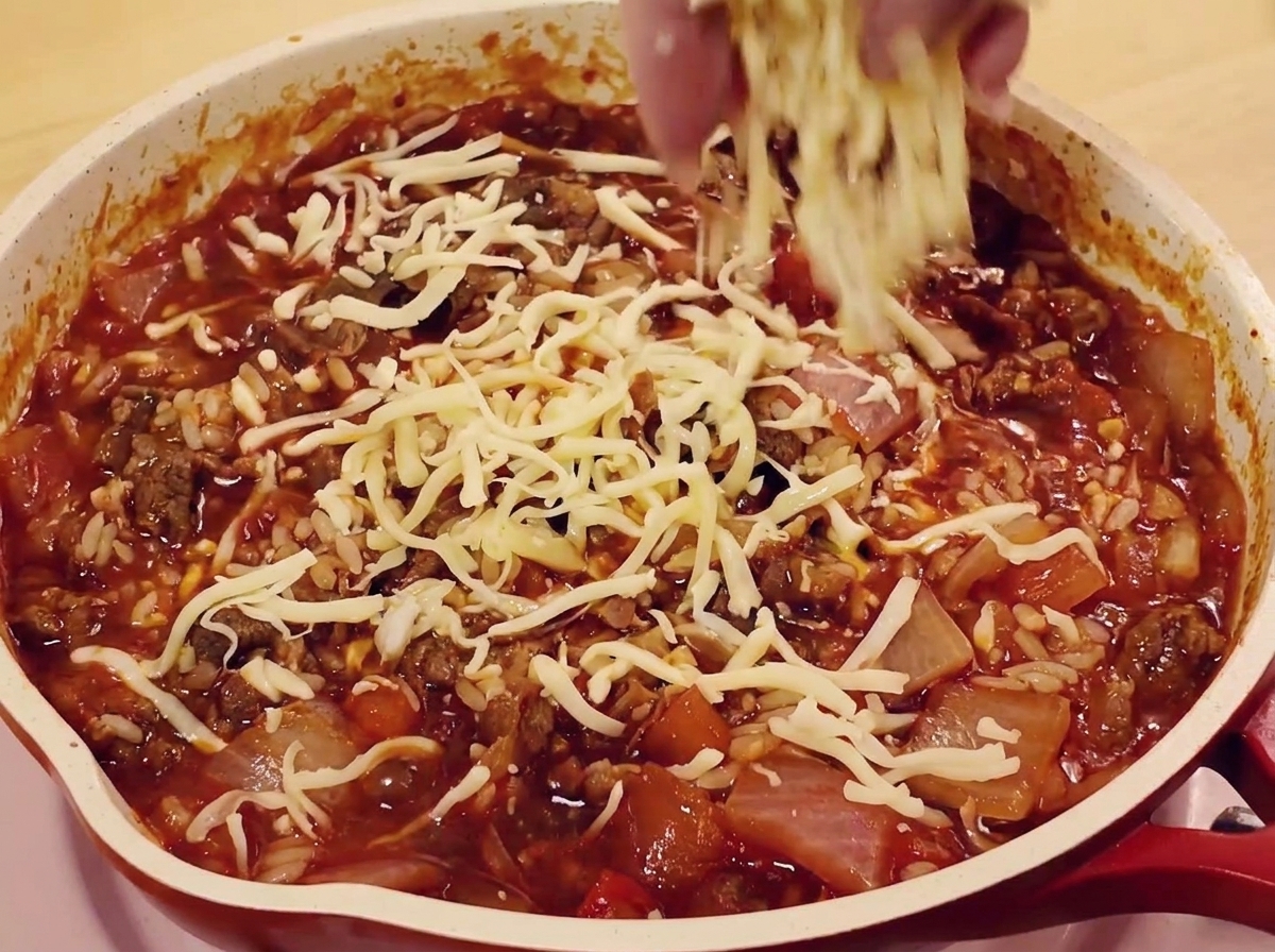 밥과 고기 위에 모차렐라 치즈를 뿌리는 모습