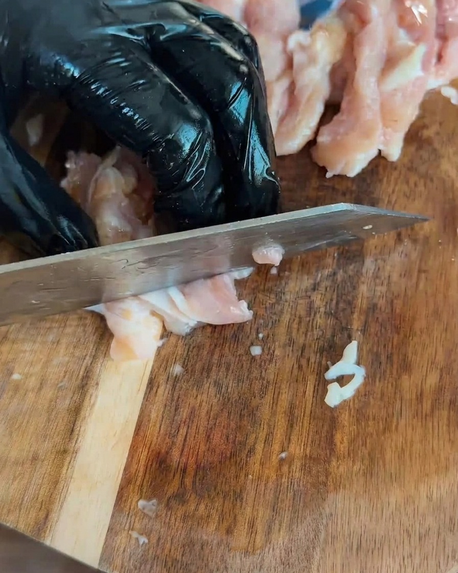 나무 도마 위에 깍둑썰기 한 생닭고기가 놓여 있는 모습
