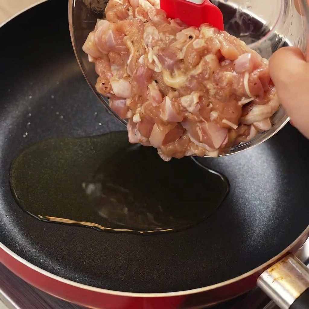 달궈진 팬에 빨간 스패츌라로 닭고기를 넣고 볶는 모습