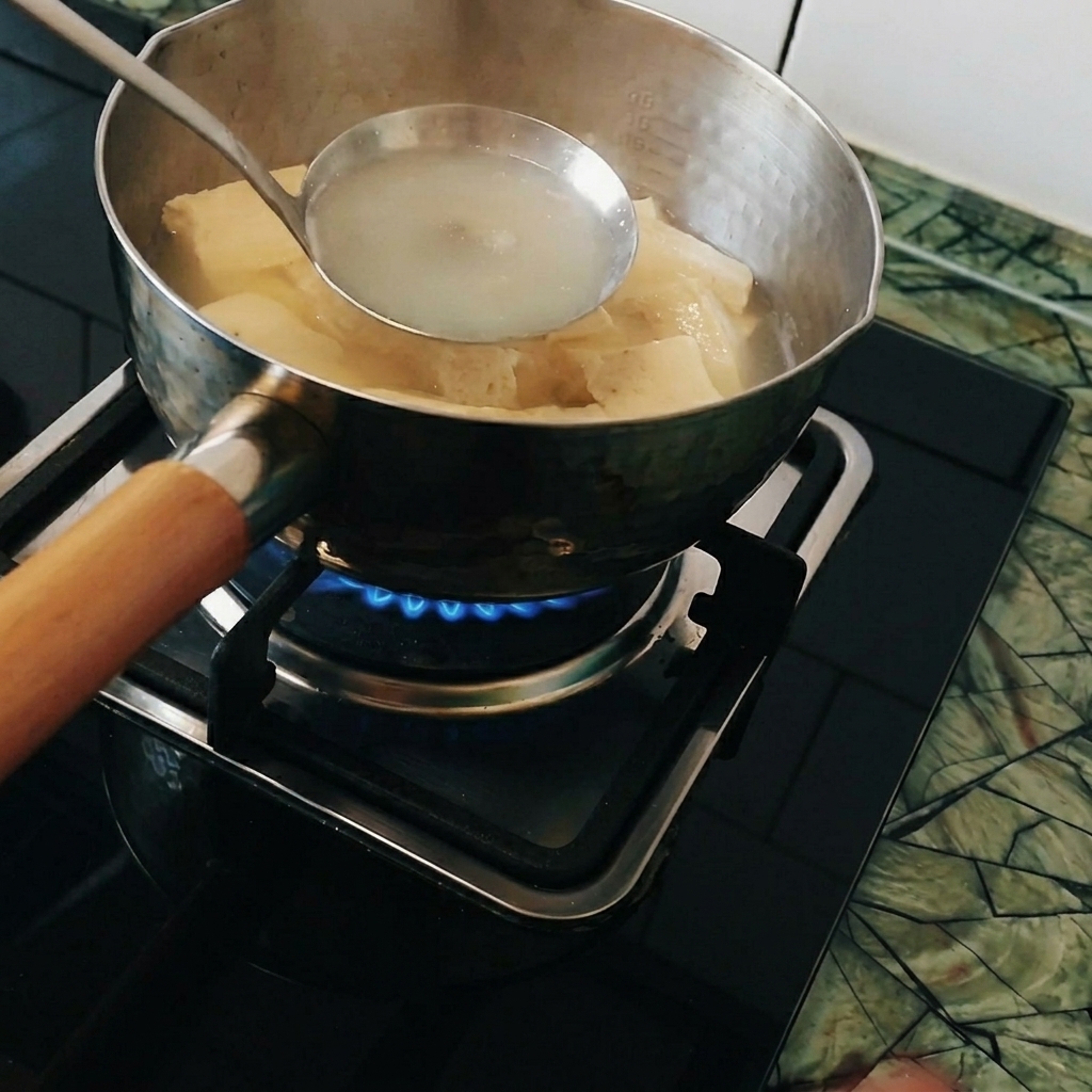 끓는 냄비 안의 국자에 고체 카레를 넣고 푸는 모습.