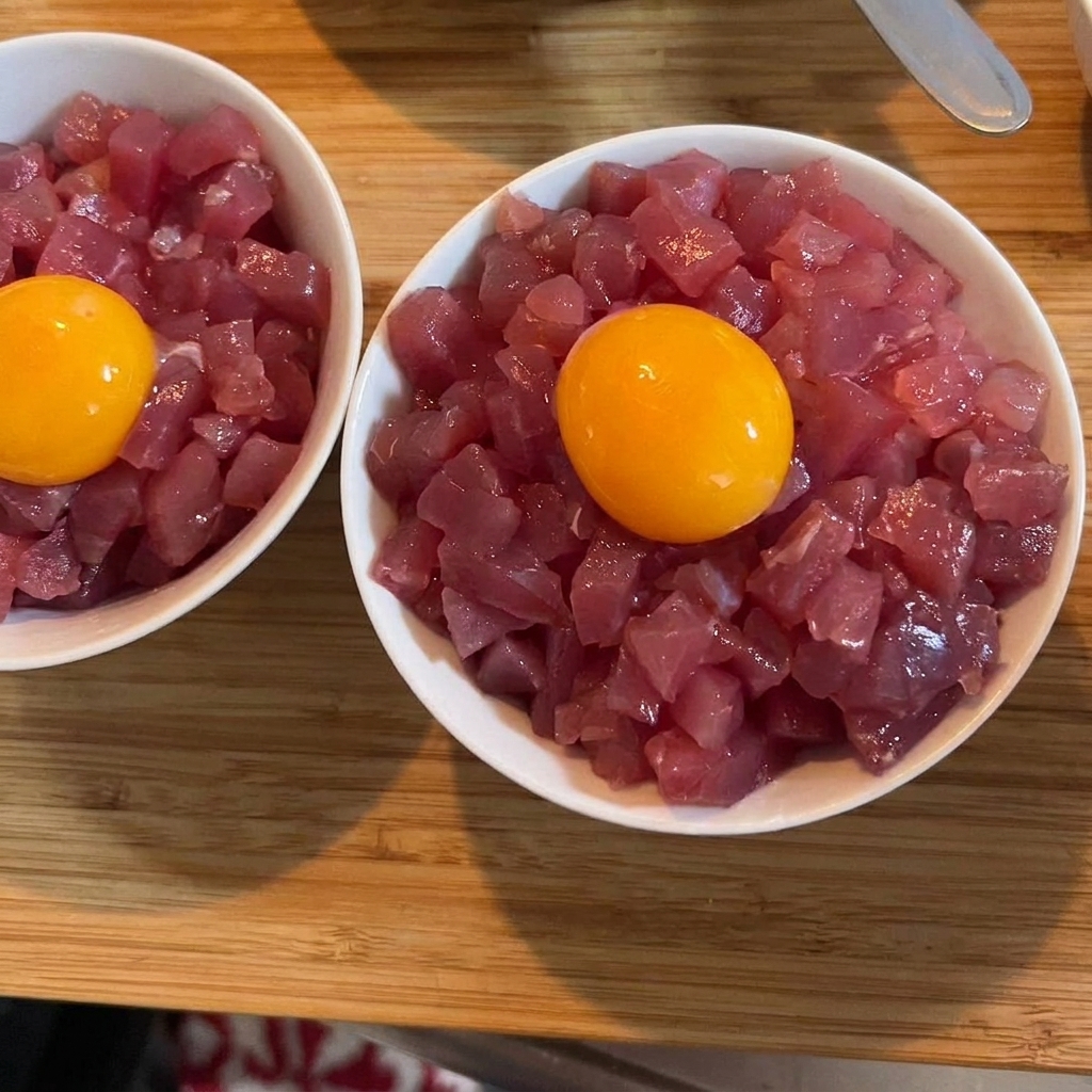 참치와 밥 위에 얹혀진 황금빛 달걀 노른자와 다진 파로 장식된 완성된 덮밥.