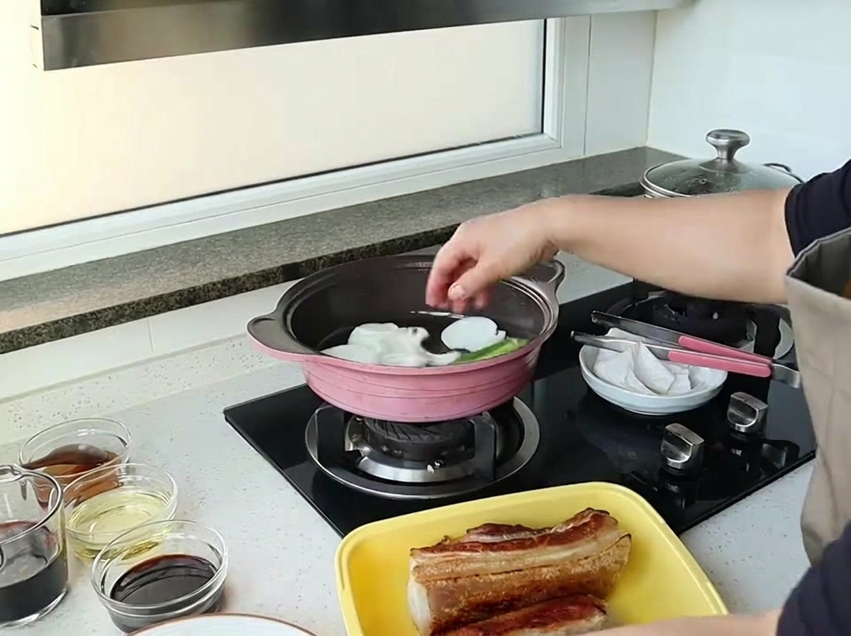 큼직하게 썬 흰 양파를 분홍색 팬에 넣는 모습.
