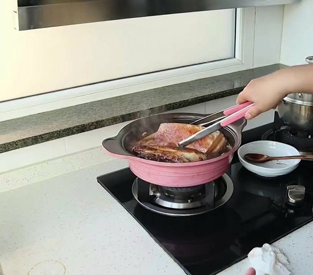 끓고 있는 소스 속 삼겹살을 집게로 뒤집는 모습.