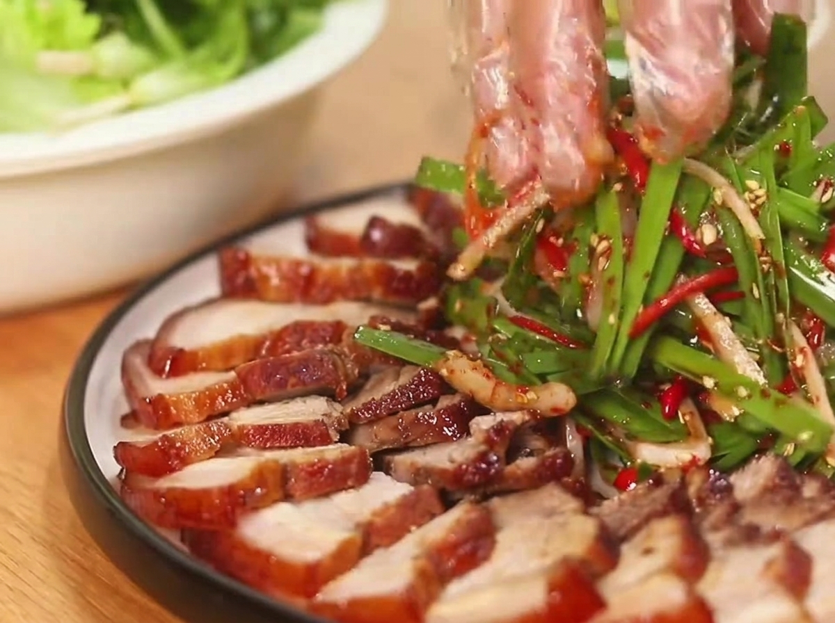 그릇에 담긴 고기 옆에 신선한 파채 샐러드를 곁들이는 모습.