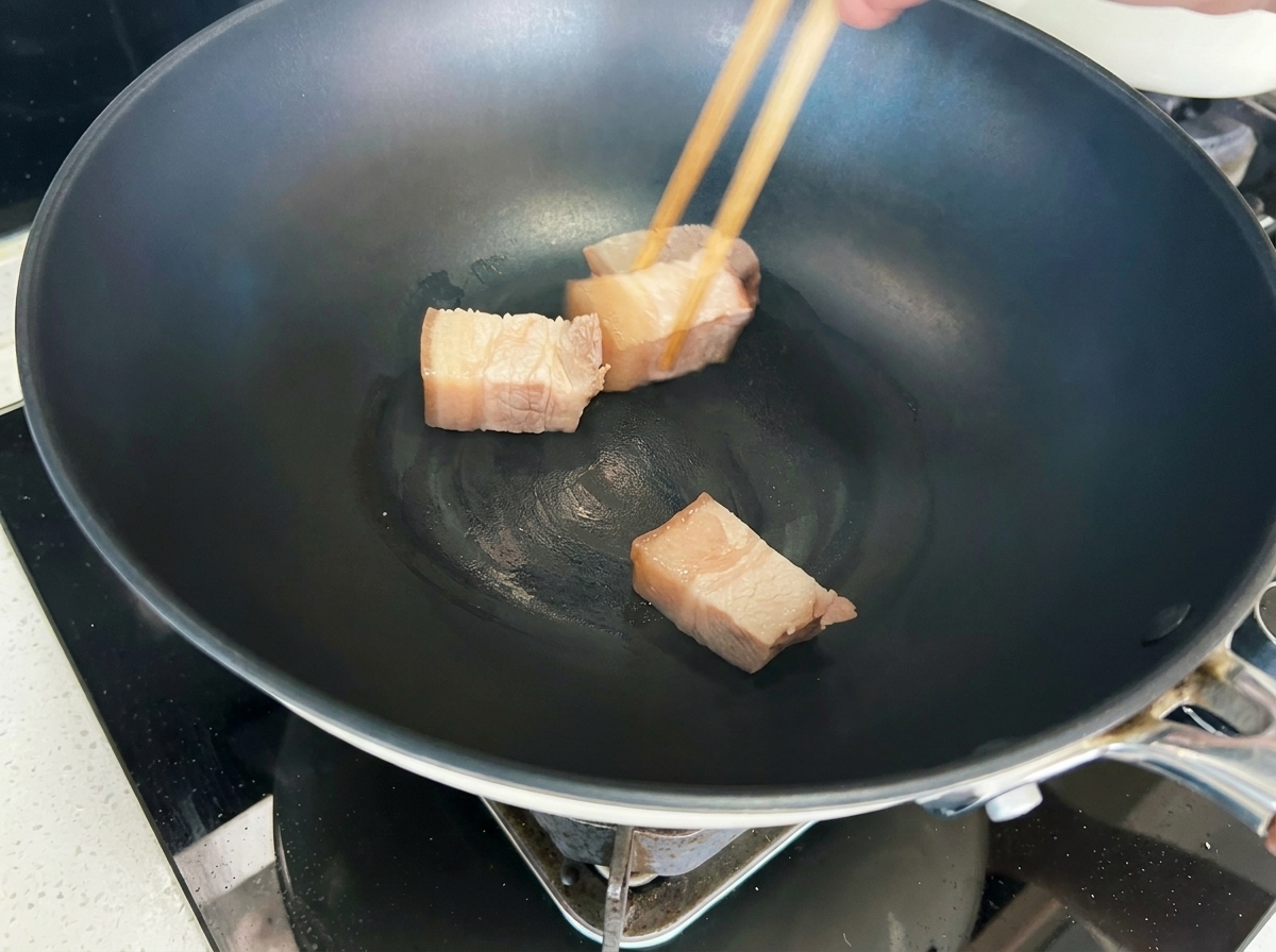 웍에서 돼지고기 큐브가 황금빛 갈색이 될 때까지 구워지는 모습.