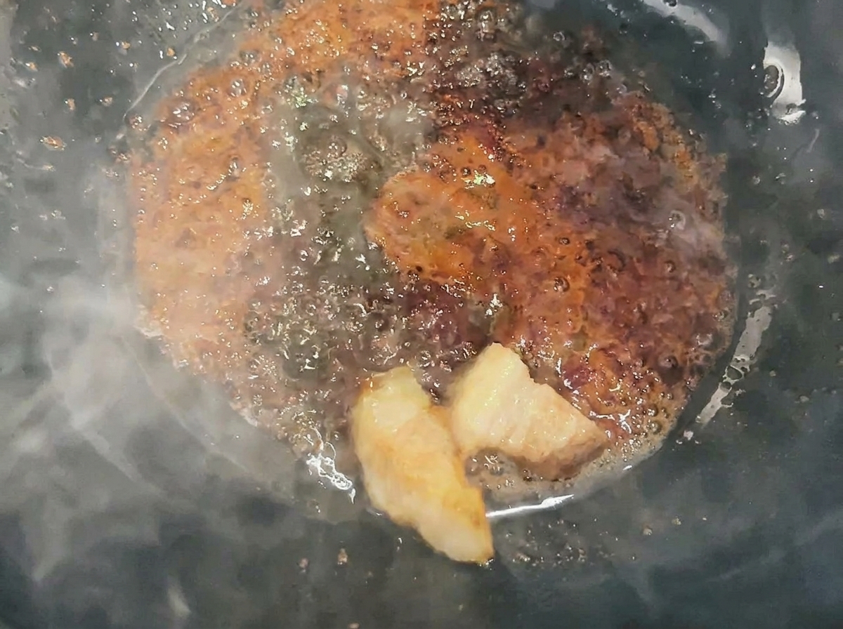 웍에서 액체 카라멜에 돼지고기 큐브를 버무리며 코팅하는 모습.