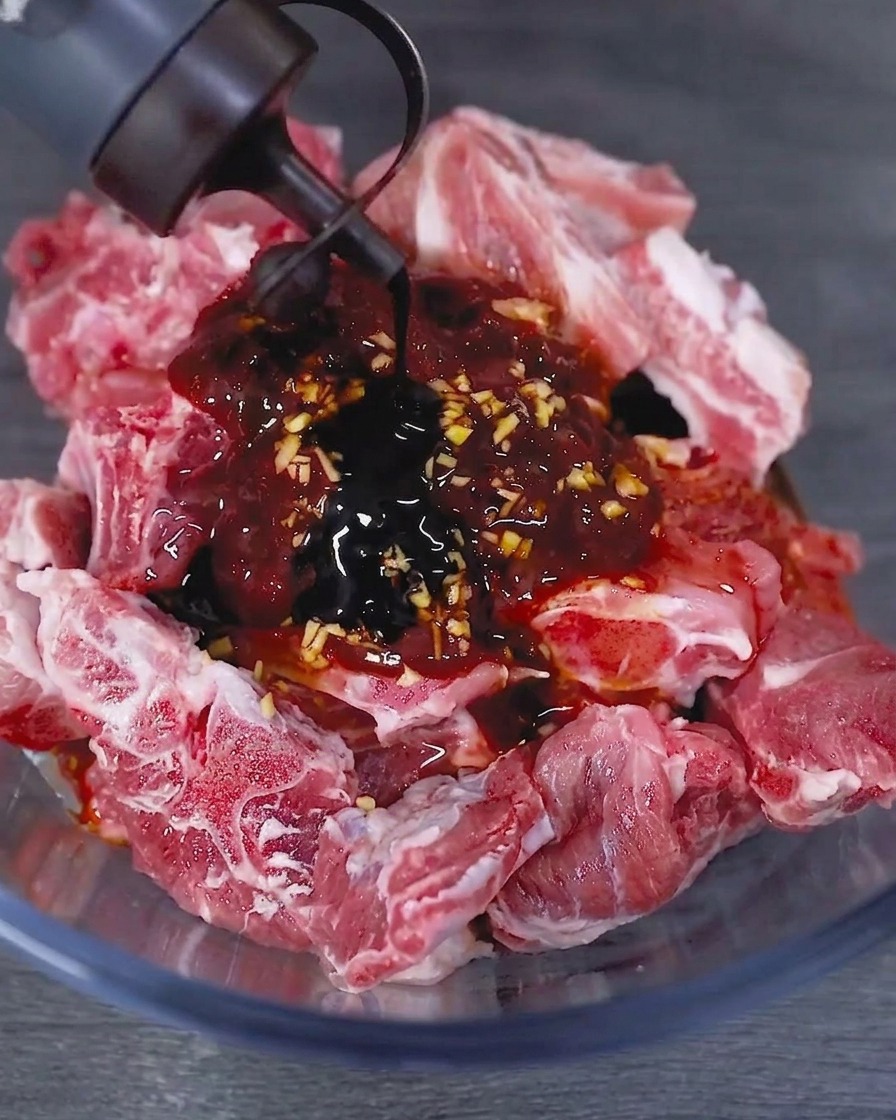 양념된 생 돼지갈비가 담긴 볼에 노추를 붓는 모습.