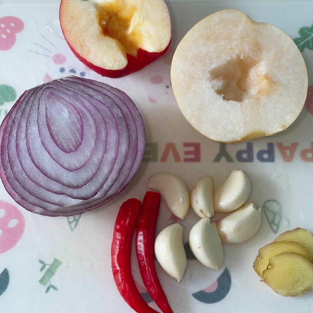 도마 위에 놓인 사과, 적양파, 배, 마늘, 홍고추, 생강.