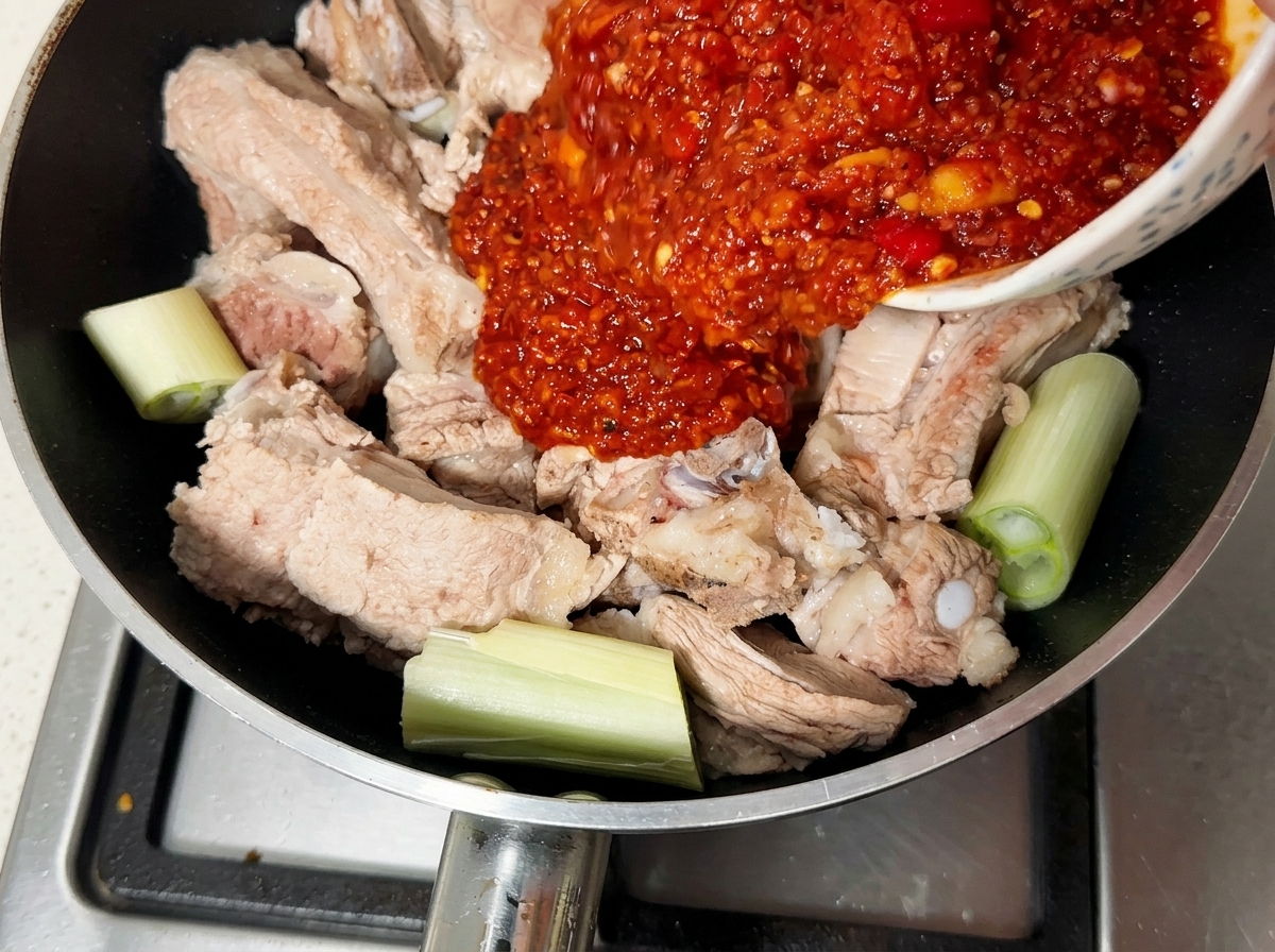 데친 돼지갈비 위로 붉은 양념장을 붓는 모습.
