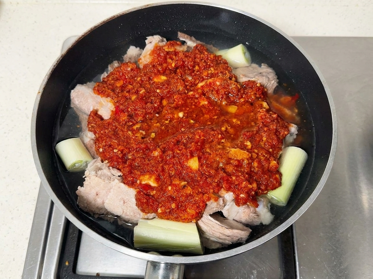 팬에 양념한 돼지갈비를 넣고 물을 부어 끓이는 모습.