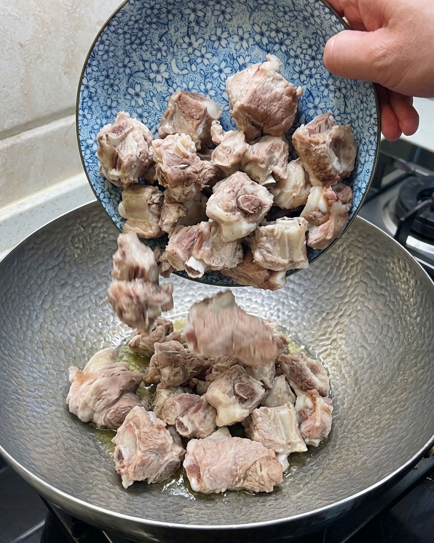 웍에서 돼지 갈비, 생강, 팔각, 건고추를 함께 볶는 모습.
