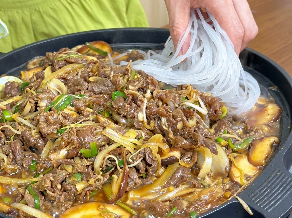 익어가는 고기 옆으로 불린 당면을 추가하는 모습.