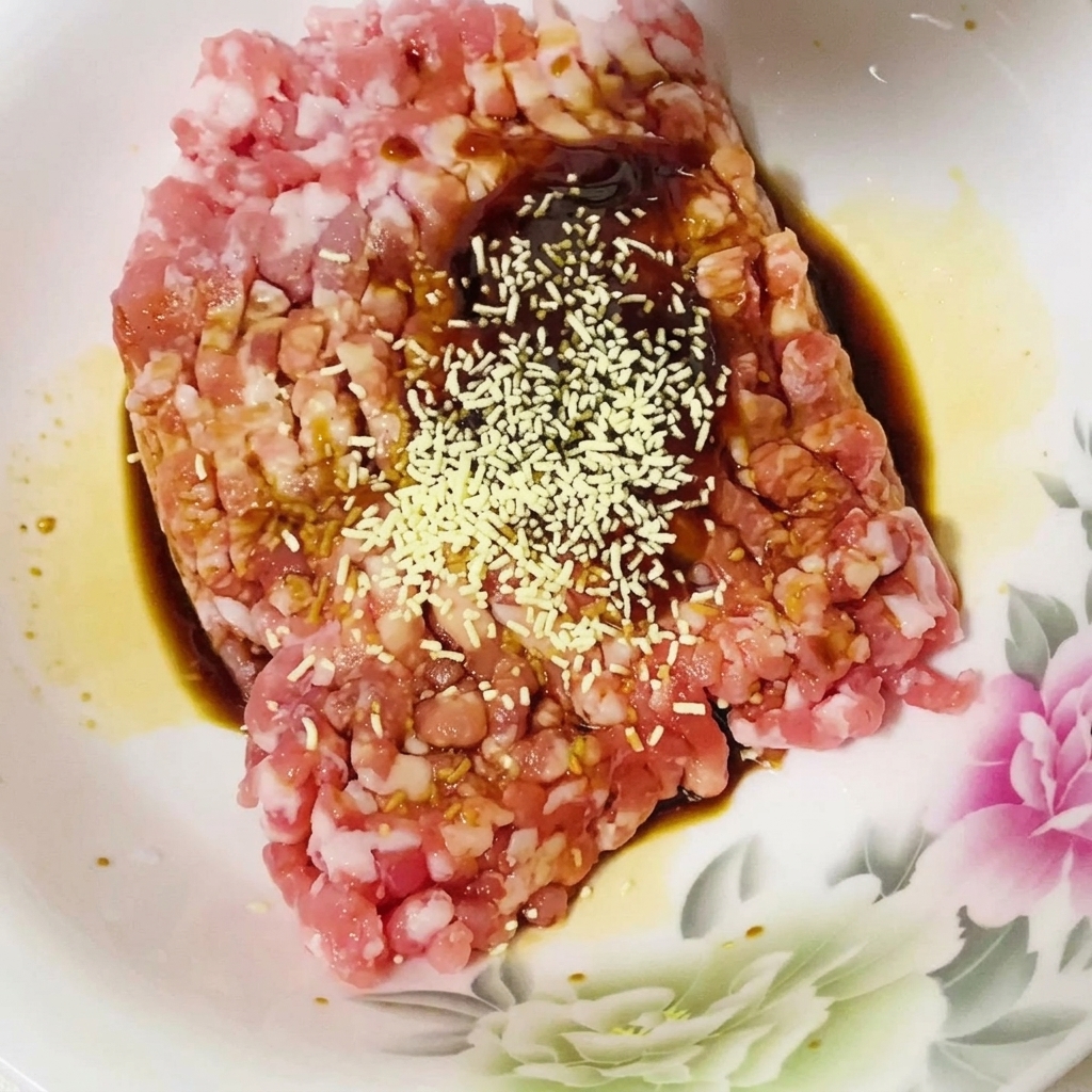 다진 돼지고기 양념 혼합물에 향신료 가루를 더하는 모습.