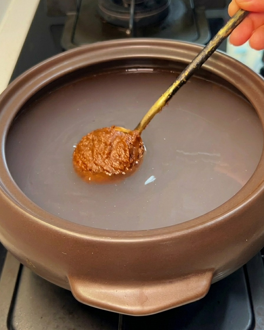 뚝배기 물에 된장을 넣고 푸는 모습.