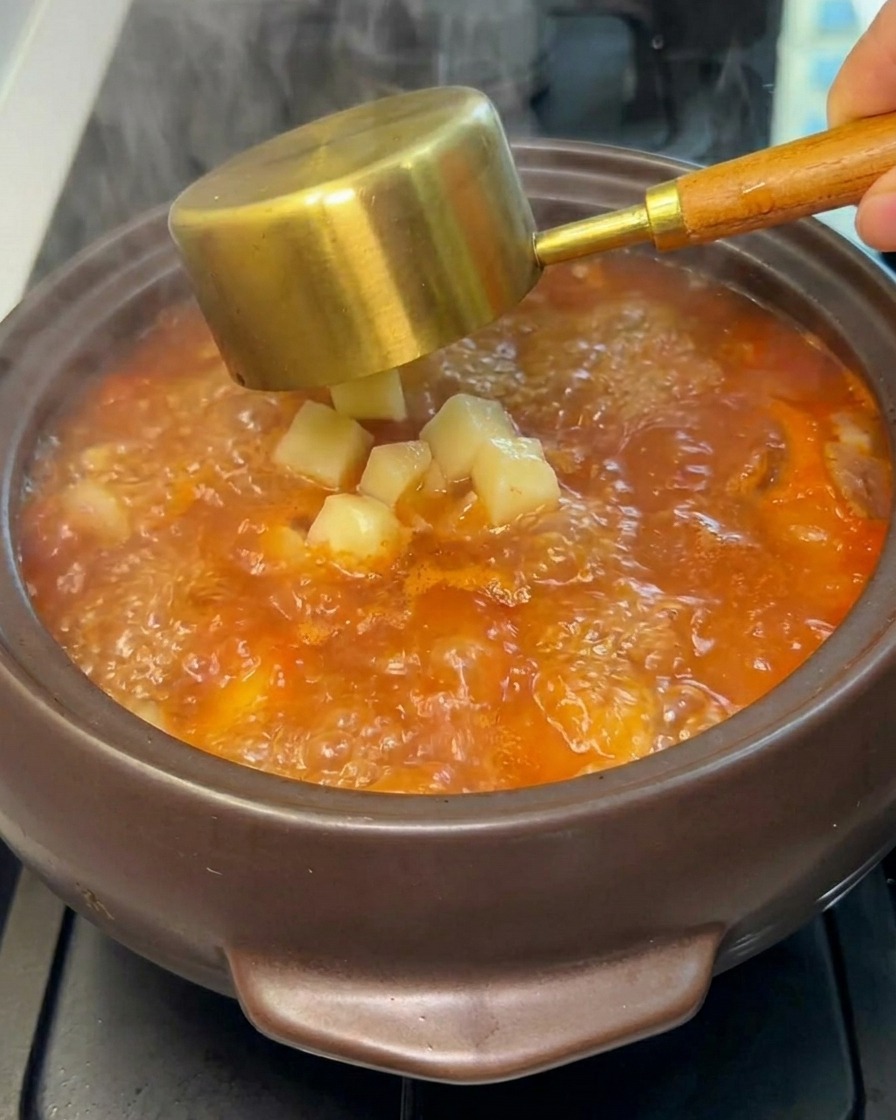 끓는 찌개에 깍둑썰기한 감자를 넣는 모습.