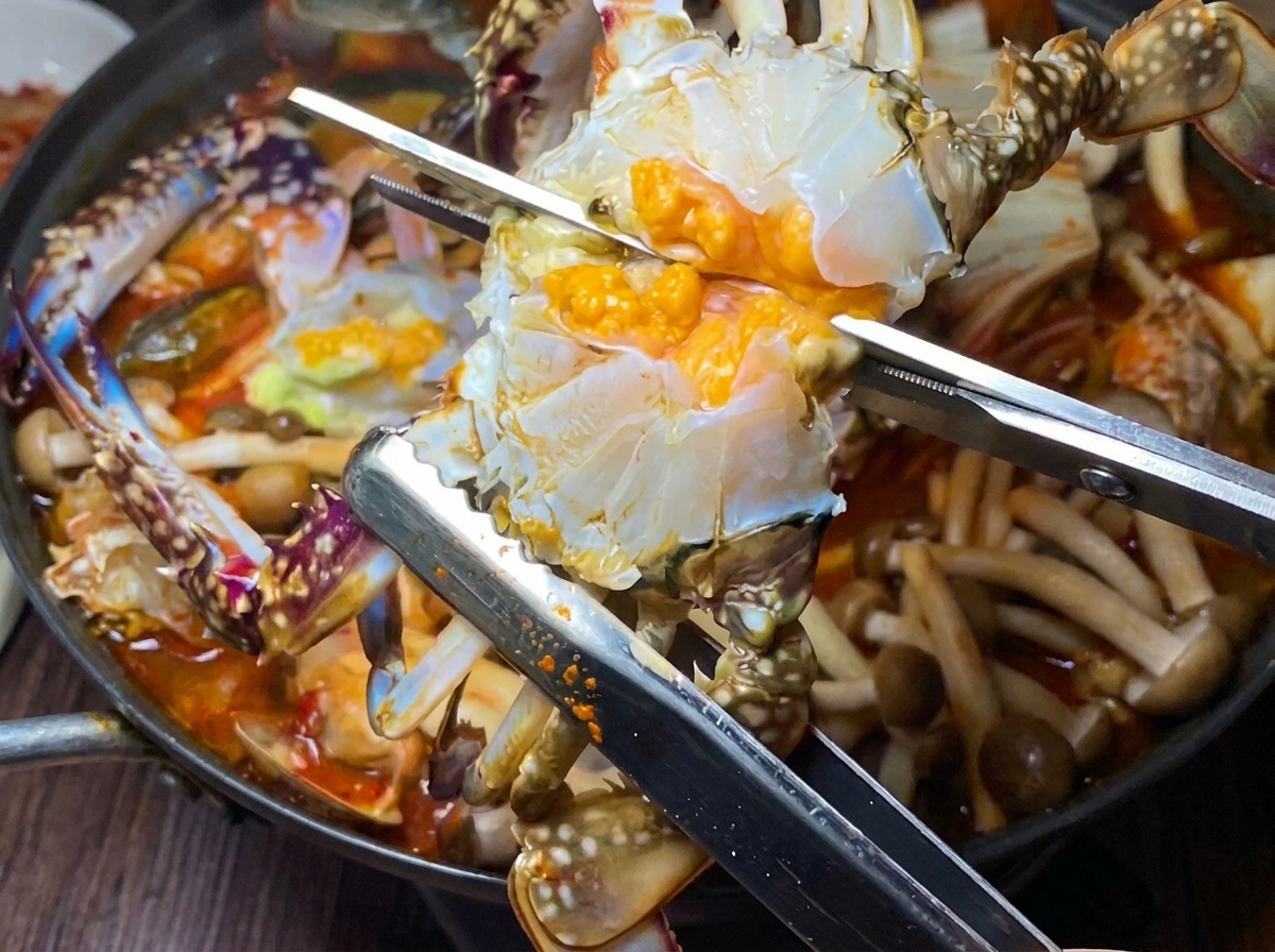 손질된 꽃게를 반으로 잘라 찌개 냄비에 넣는 모습.