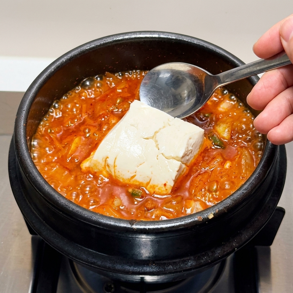 끓는 찌개에 순두부를 조심스럽게 넣는 모습.