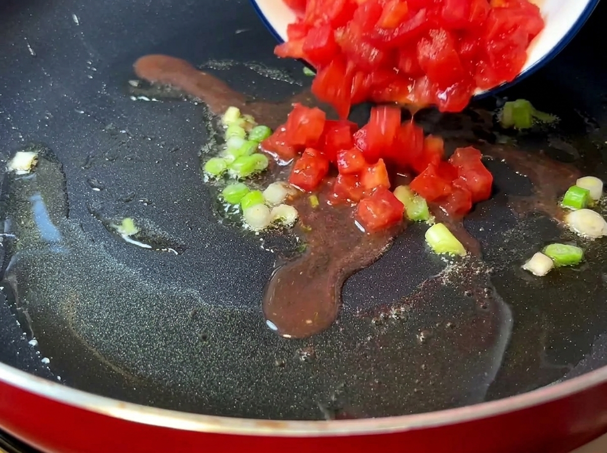 냄비에서 잘게 썬 토마토가 으깨지며 즙이 나오는 모습.